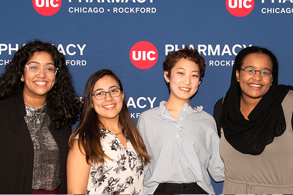 diverse students in front of backdrop with college of pharmacy logo